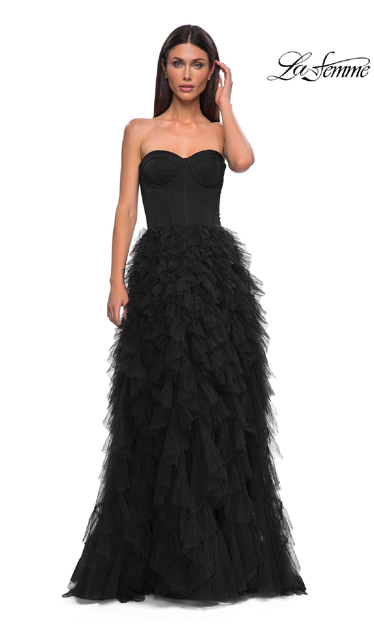 A woman models the Strapless Long Ruffled Prom Dress: La Femme 32760, featuring a fitted corset bodice and layered tulle skirt, standing against a white background with the